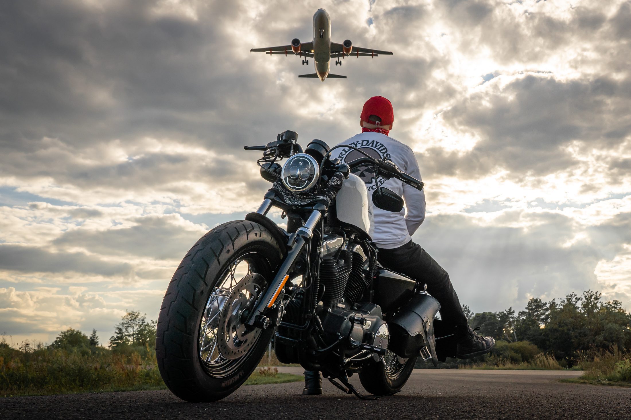 Motorradfahrer beobachtet ein startendes Flugzeug am Himmel