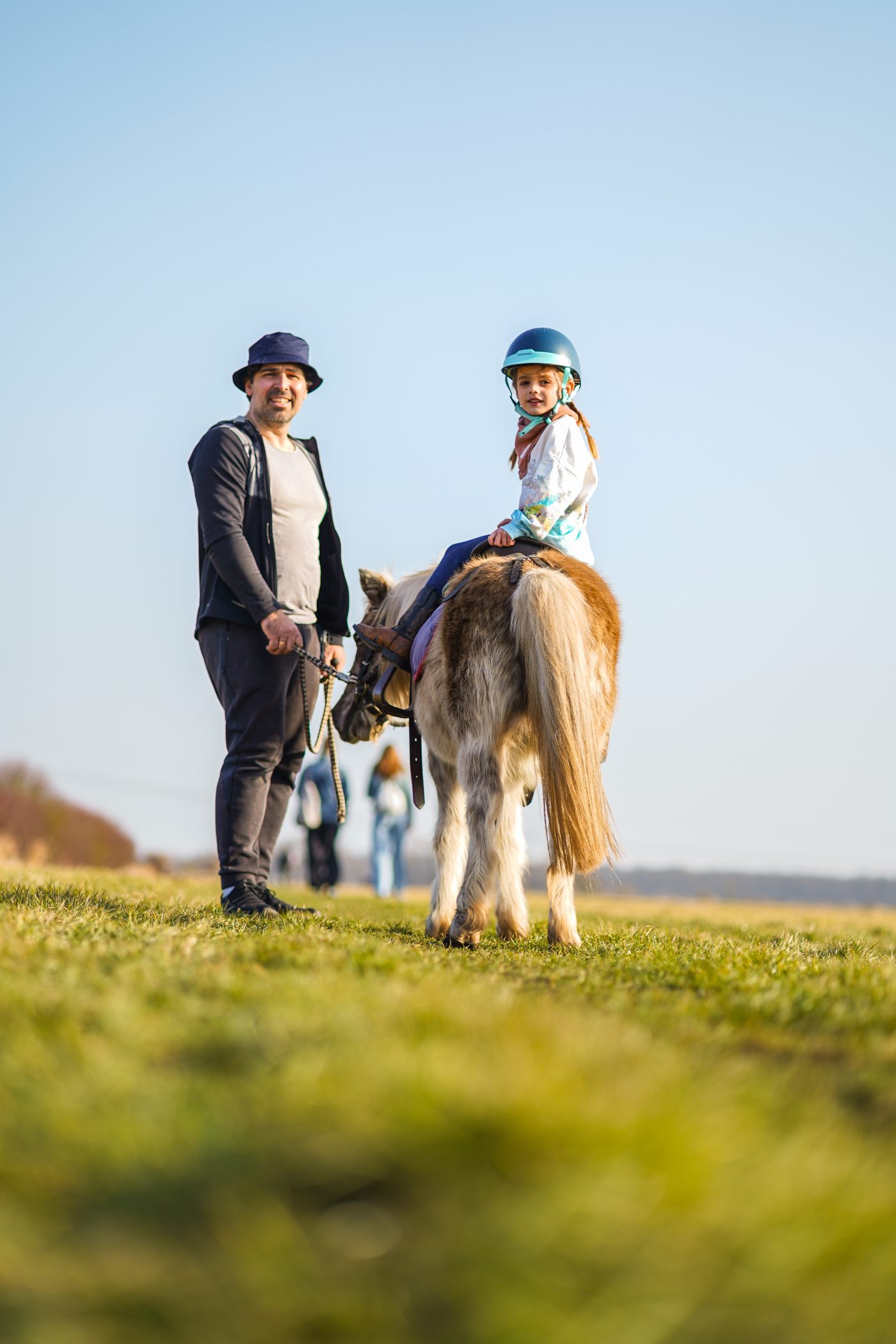Vater und Tochter mit Pony auf der Wiese