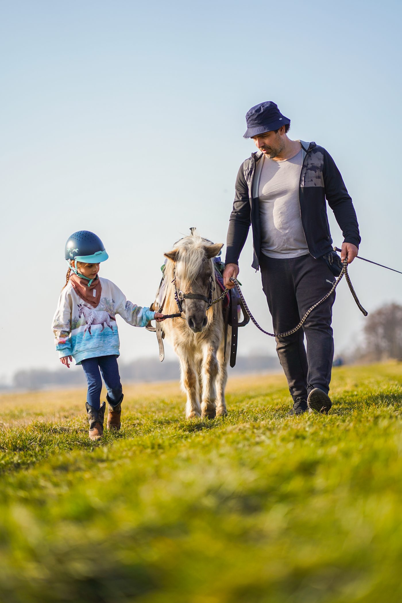 Vater und Tochter führen gemeinsam ein Pony